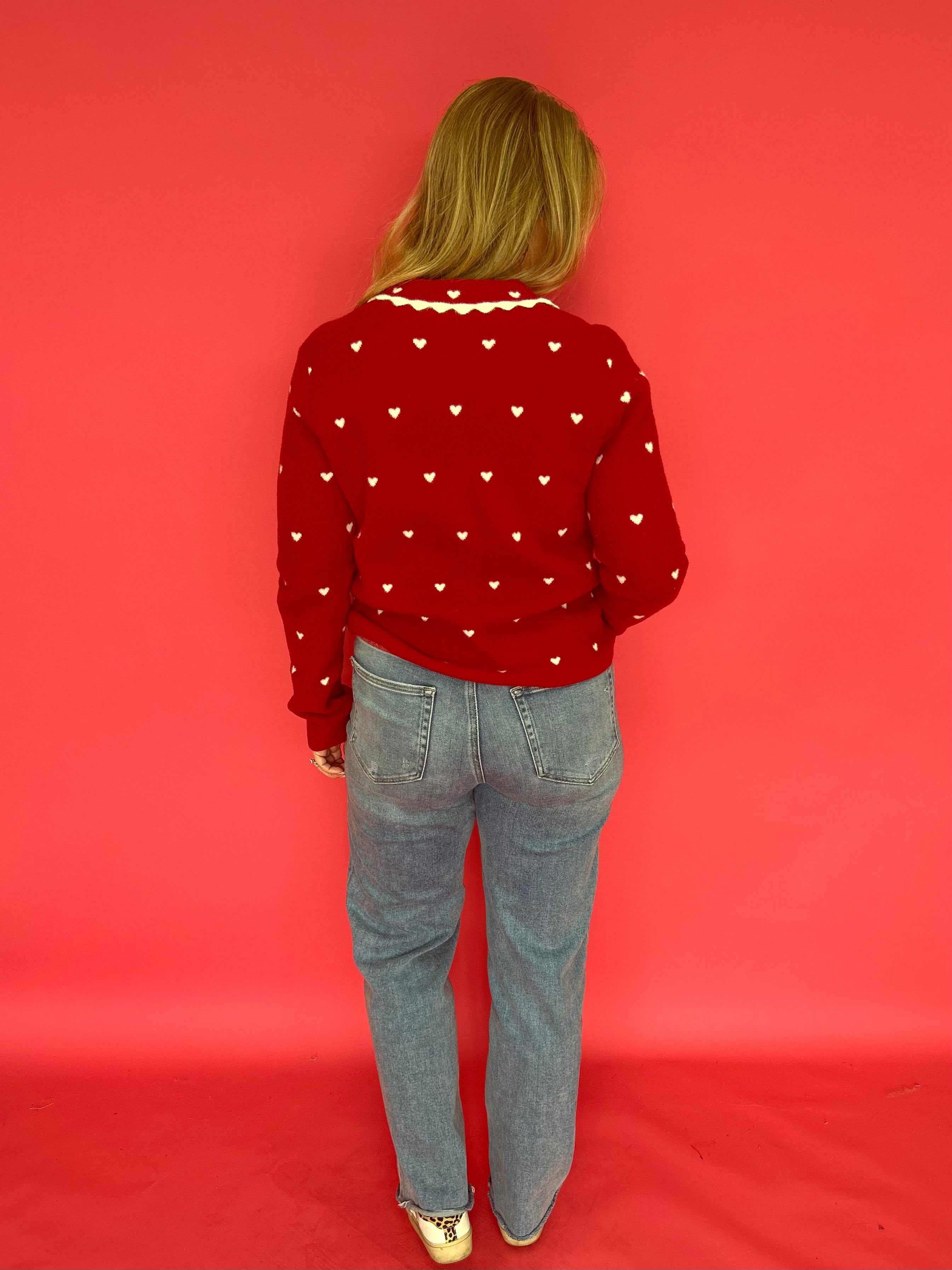 Side view of the red heart print button-up sweater showing the long sleeves and soft drape