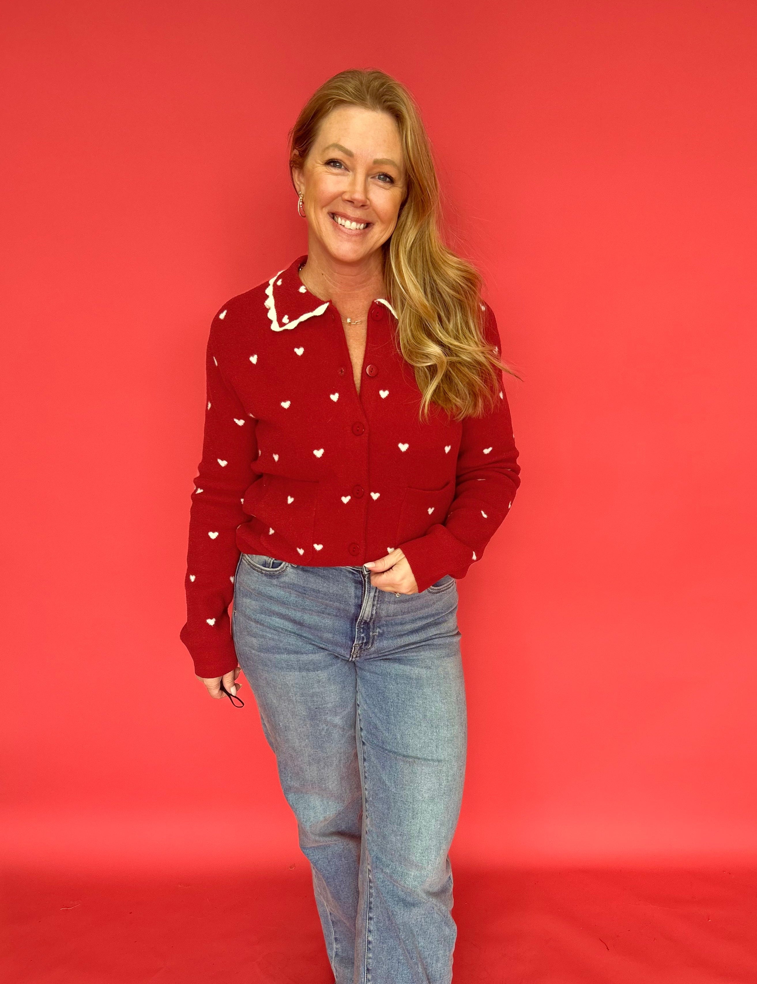 Close-up of the scalloped heart collar and button placket on the red heart print sweater