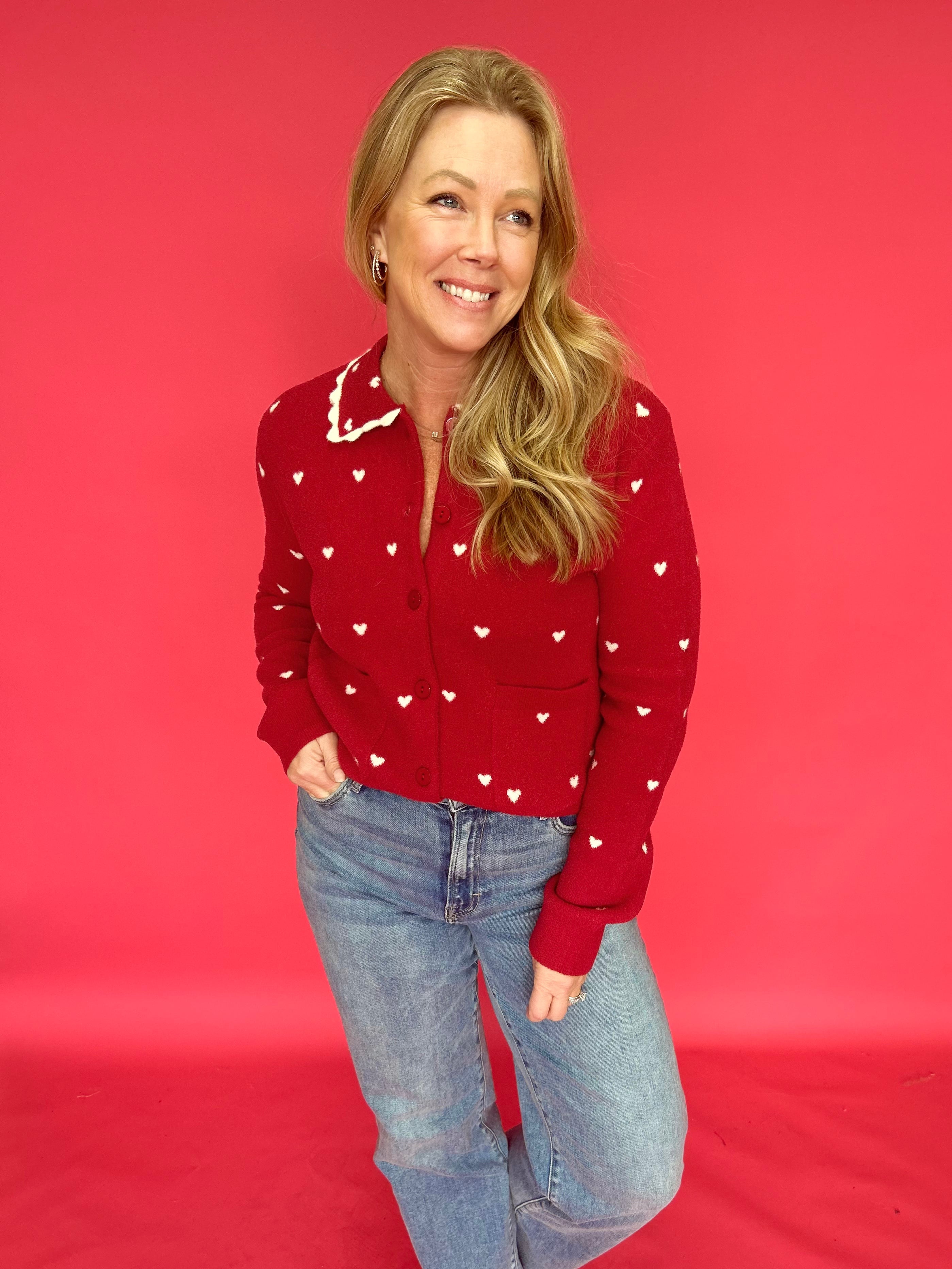Woman styling the heart print button-up sweater open over a tank with high-rise denim