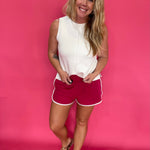 Close-up of the contrast piping along the curved dolphin hem on the pink cotton shorts