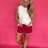 Close-up of the contrast piping along the curved dolphin hem on the pink cotton shorts
