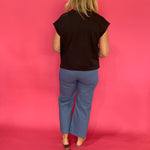 Full length view of the black scuba knit short sleeve top front tucked into denim