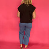 Full length view of the black scuba knit short sleeve top front tucked into denim