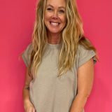 Woman wearing a mocha scuba knit short sleeve top with a relaxed fit styled with denim and sneakers