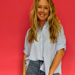 Woman wearing a blue oversized short sleeve button down shirt worn loose over shorts