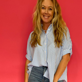 Woman wearing a blue oversized short sleeve button down shirt worn loose over shorts
