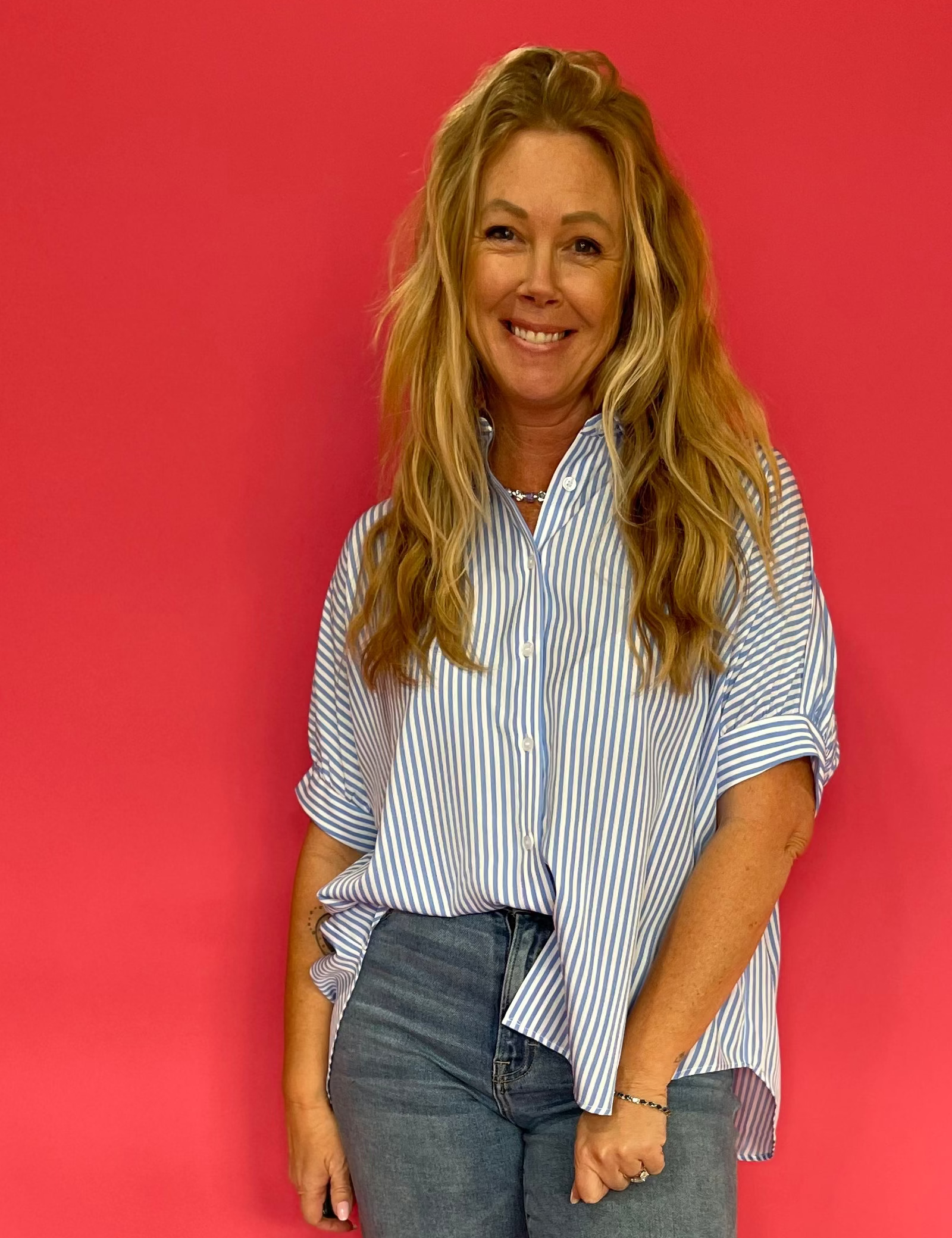 Woman wearing a blue oversized short sleeve button down shirt worn loose over shorts