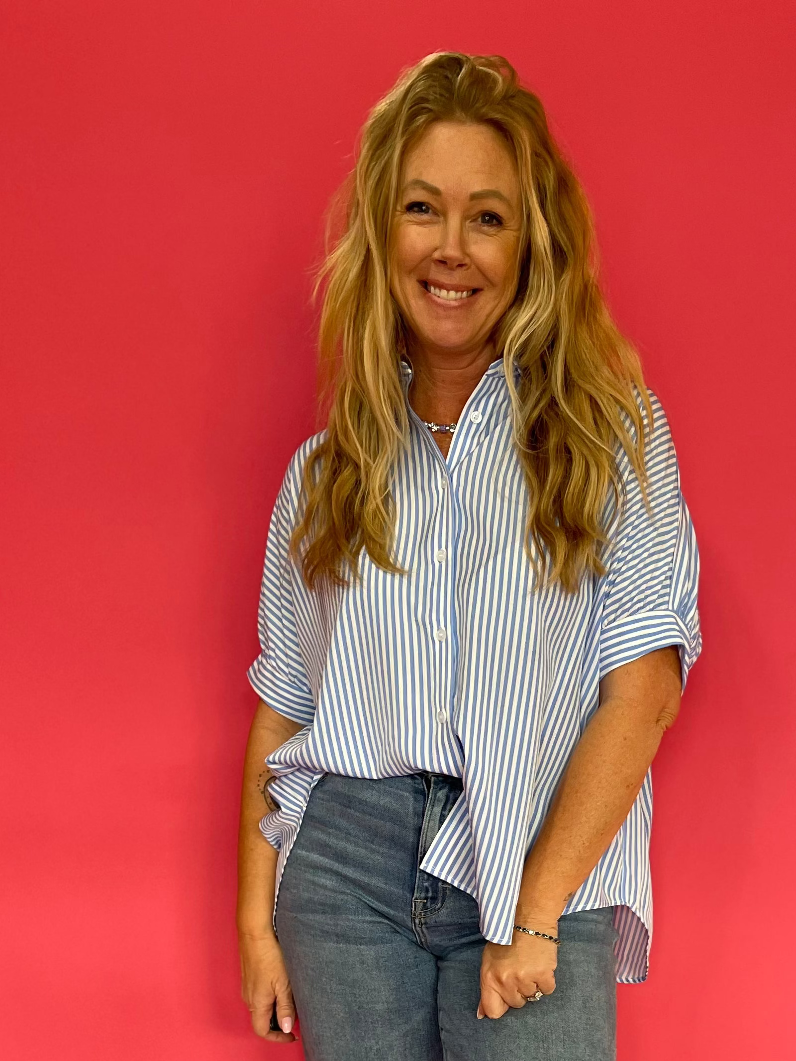 Woman wearing a blue oversized short sleeve button down shirt worn loose over shorts
