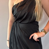 Side view showing the fluid drape and midi length of the black one-shoulder dress