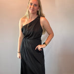 Full length view of the black one-shoulder dress styled with heels for an evening event