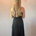 Black draped one-shoulder dress styled for a wedding reception with simple jewelry and a clutch
