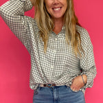 Woman wearing an emerald green plaid flannel button down shirt open over a fitted tank
