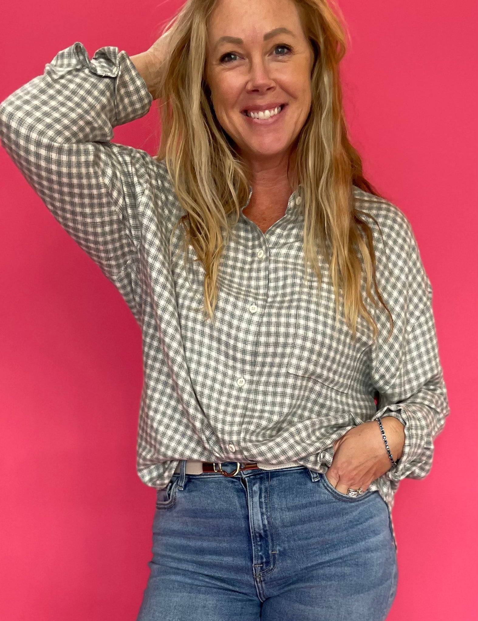 Woman wearing an emerald green plaid flannel button down shirt open over a fitted tank