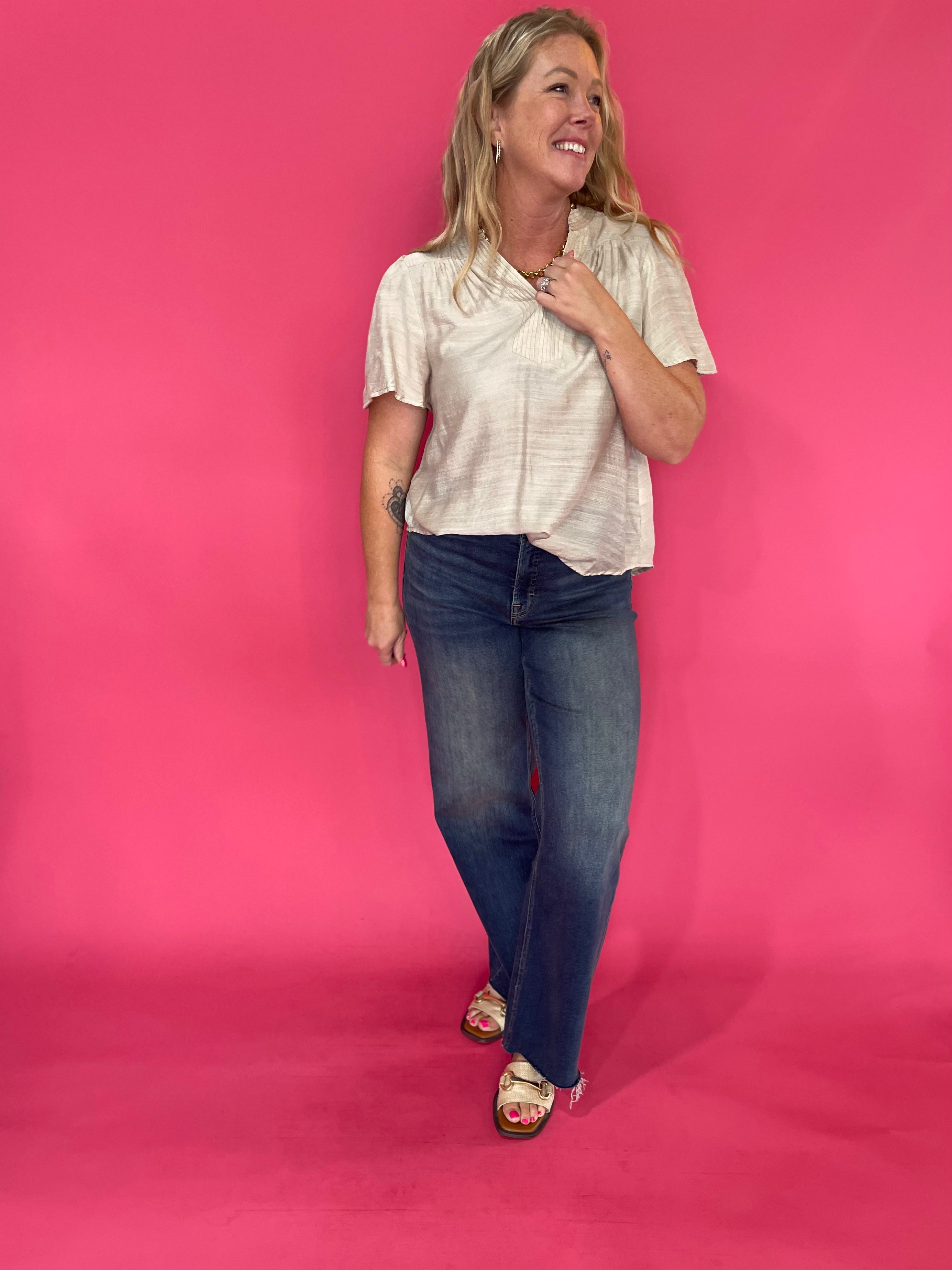 Detail of the pintucked texture and soft drape on the lightweight neutral oatmeal woven blouse
