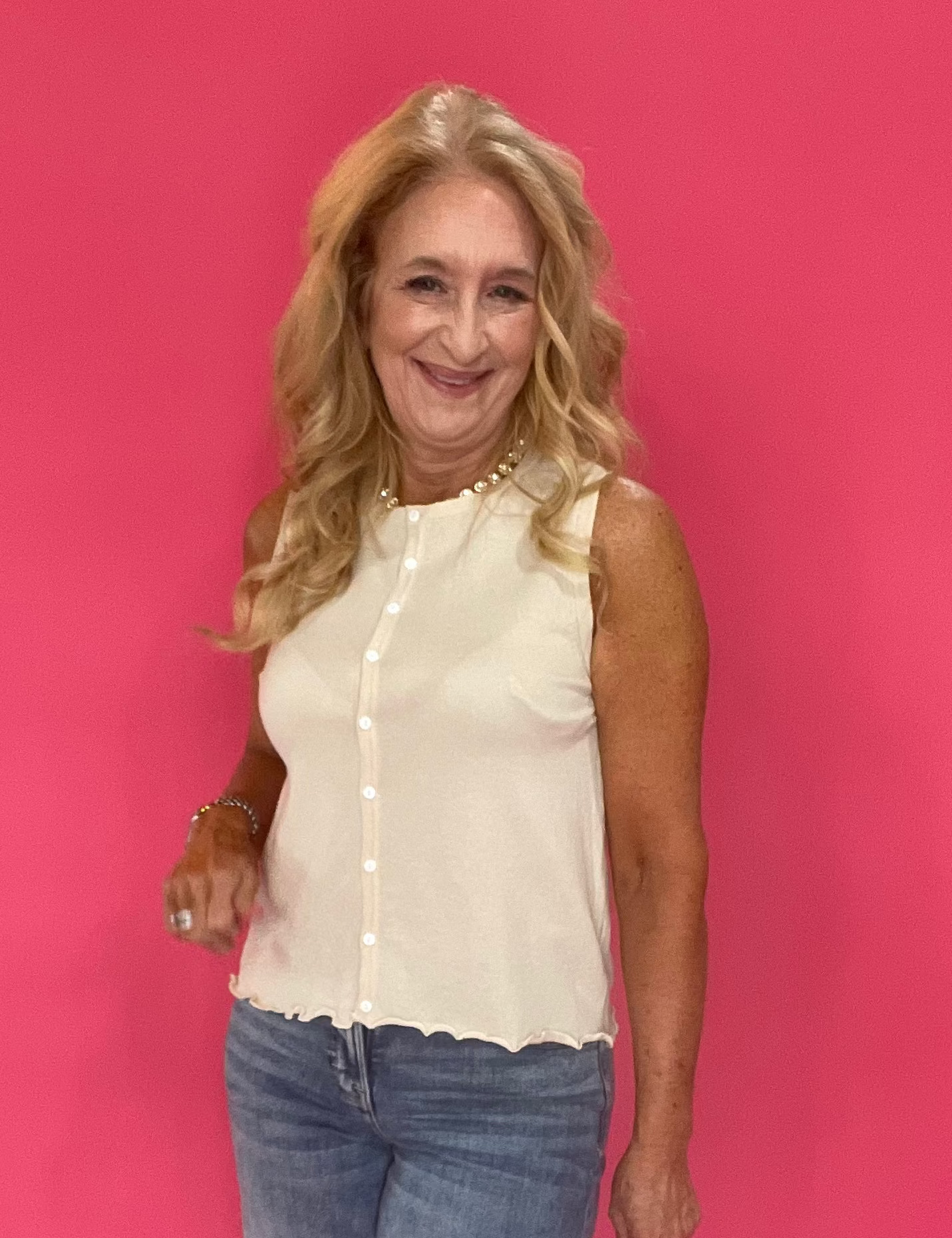 Woman wearing a neutral button front sweater tank with a printed skirt and sandals