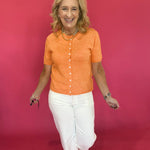 Back view of the tangerine orange button cardigan showing its relaxed, easy short sleeve fit
