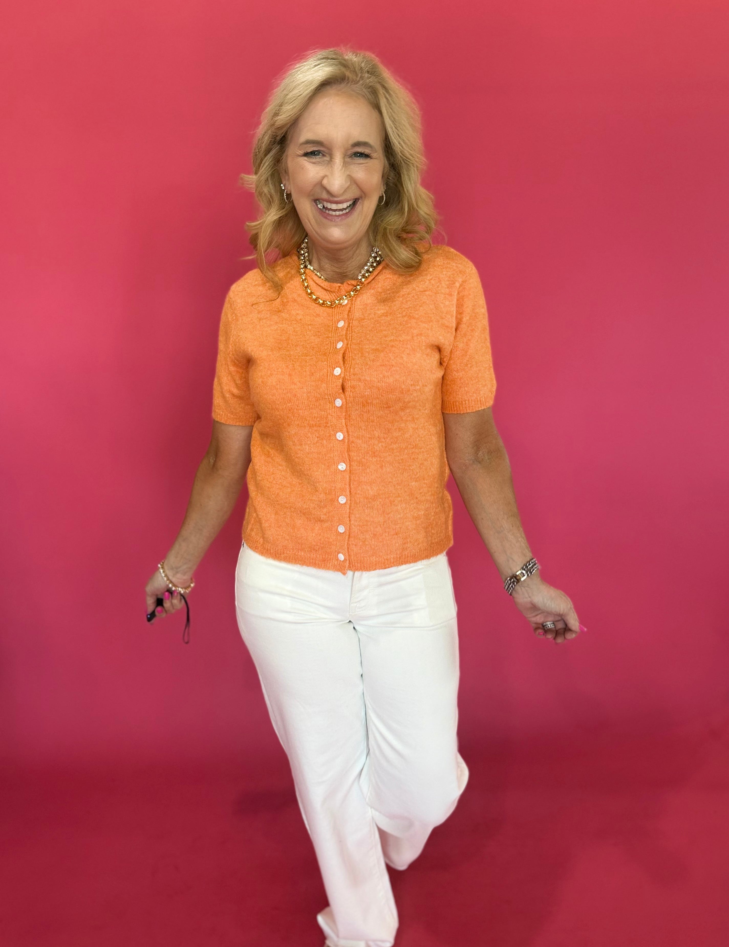 Back view of the tangerine orange button cardigan showing its relaxed, easy short sleeve fit