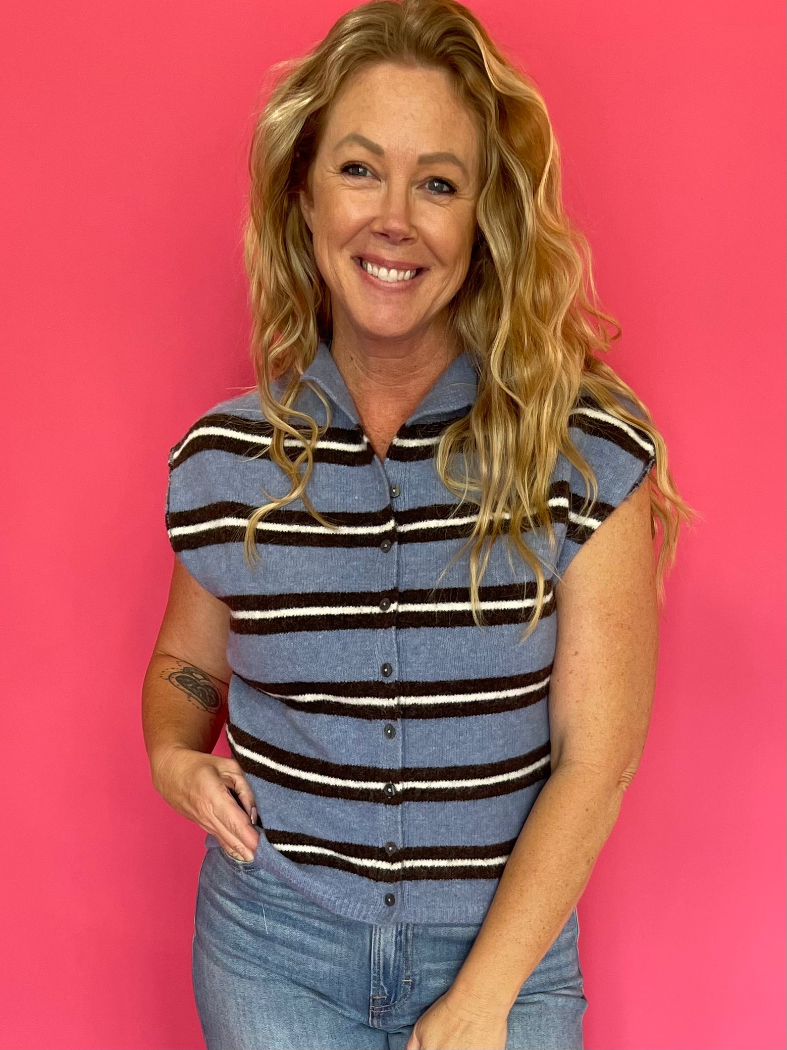 Woman wearing a blue and white striped sleeveless top with denim and white sneakers