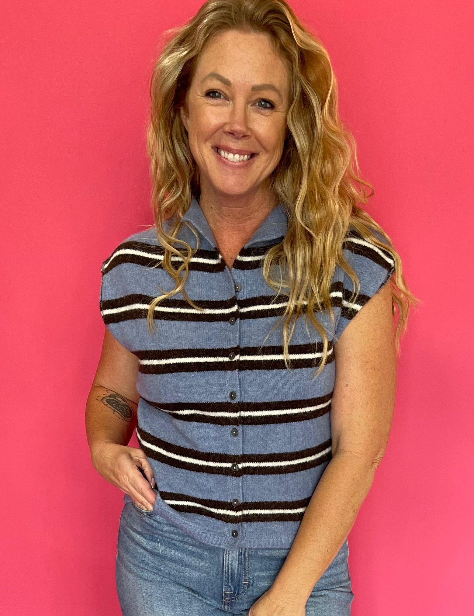 Woman wearing a blue and white striped sleeveless top with denim and white sneakers