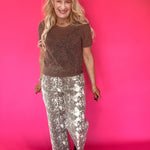 Detail of the elastic waistband and gathered front of the ecru snake print pants