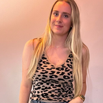 Woman wearing a leopard print top and blue jeans against a plain background