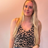 Woman wearing a leopard print top and blue jeans against a plain background