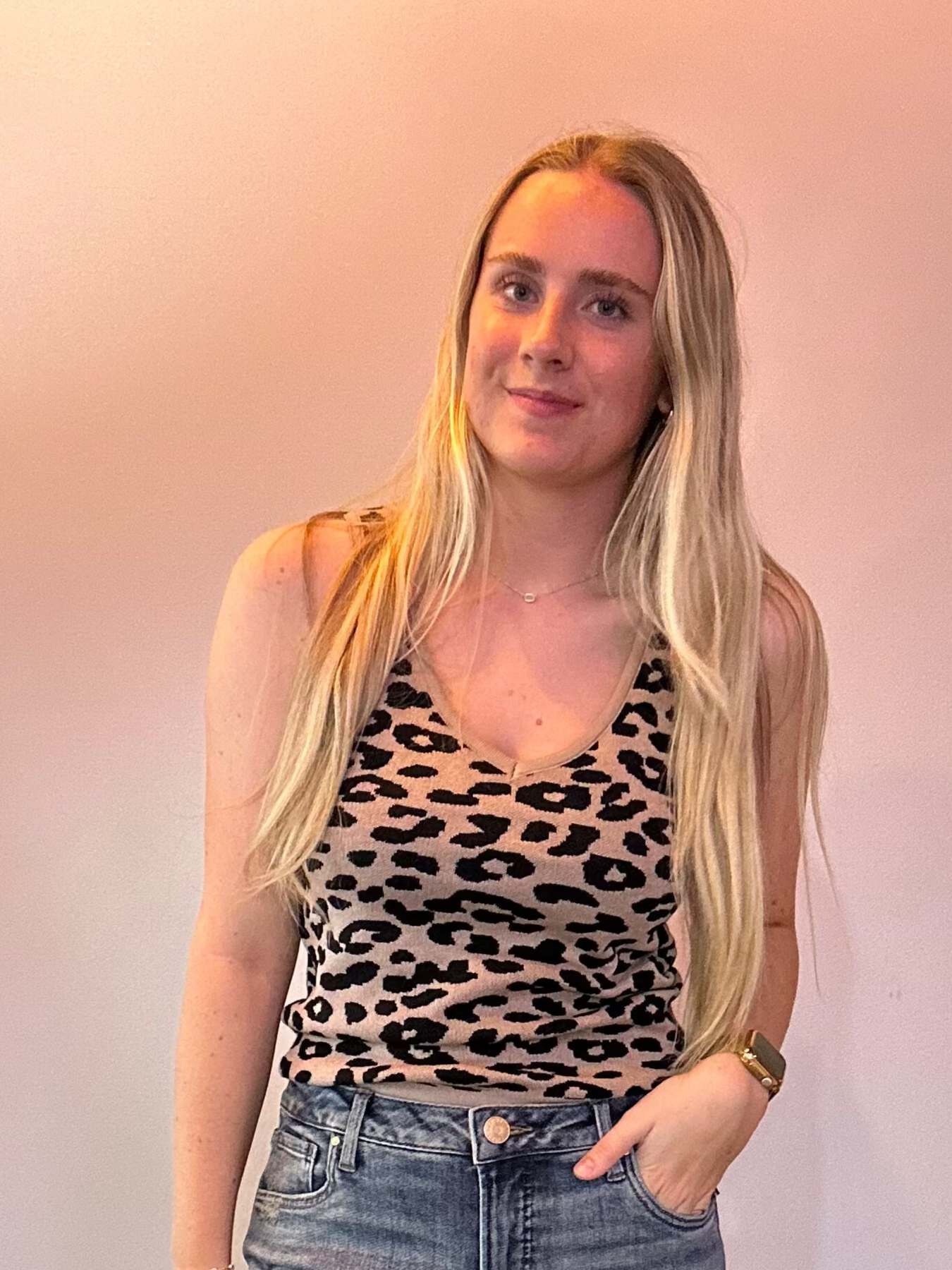 Woman wearing a leopard print top and blue jeans against a plain background
